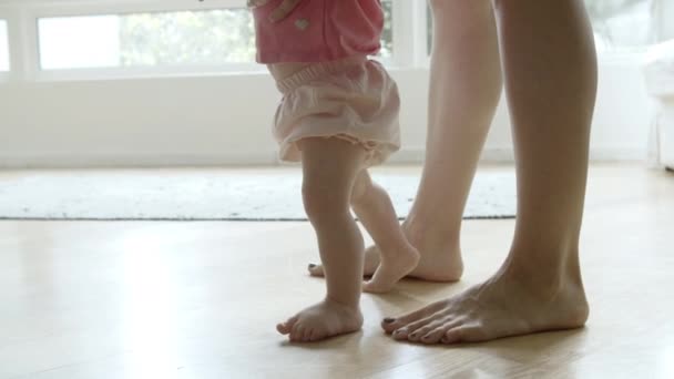 Cute boso dziecko nauka chodzenia z pomocą matki na podłodze - Materiał filmowy, wideo