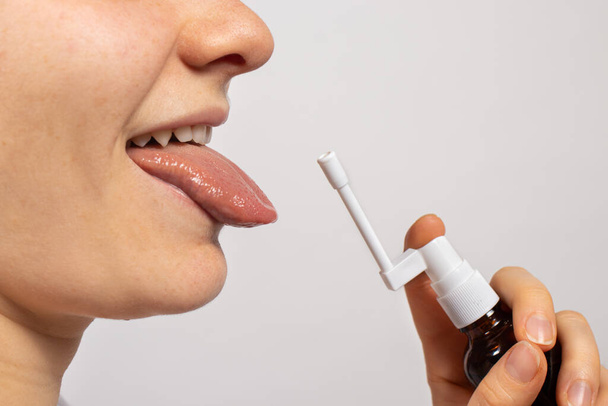 Um homem pulveriza um spray na cavidade oral a partir de candidíase da mucosa oral. Thrush, candida, pulverizem o medicamento na boca. Medicamentos, terapia e tratamento de um doente. - Foto, Imagem