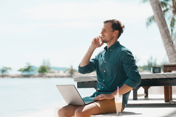 Man freelancer working with laptop at the beach in resort - Foto, Imagem