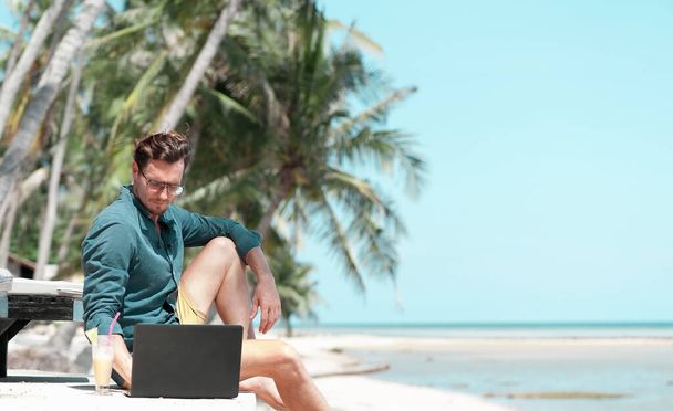 Man freelancer working with laptop at the beach in resort - 写真・画像