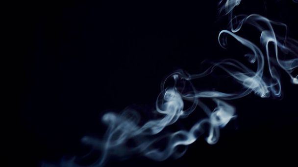 unhealthy lifestyle . cigarette smoke clouds draws artistic abstract patterns. dark background - 写真・画像