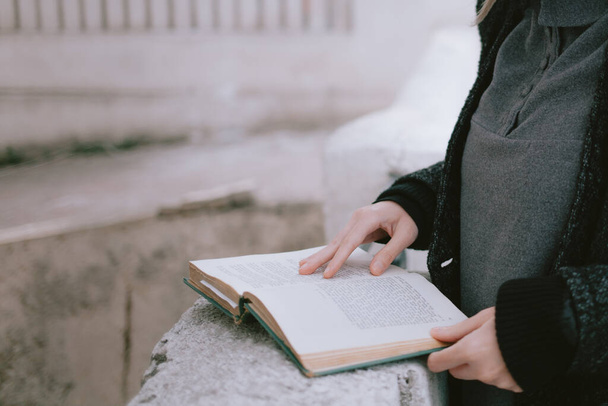 Detalle de una joven estudiante leyendo un libro al aire libre en el campus universitario - Foto, imagen