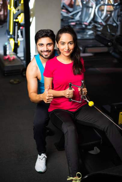 Indiaas Aziatisch jong stel is aan het trainen in de sportschool. Aantrekkelijke vrouw en knappe fitnessman trainen in moderne fitnessruimte - gezondheids- en fitnessconcept - Foto, afbeelding