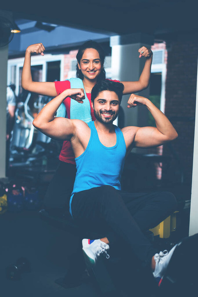 India asiática joven pareja está trabajando en el gimnasio. Mujer atractiva y hombre guapo ajuste están entrenando en el gimnasio moderno - concepto de salud y fitness - Foto, Imagen