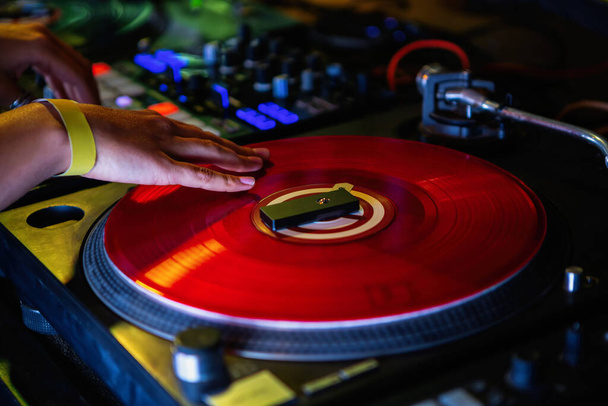 Dj girl scratches vinyl record with music on hip hop party in nightclub.Professional female disc jockey scratching records on battle.Pro djs setup for live performance on concert.Stage audio equipment - 写真・画像