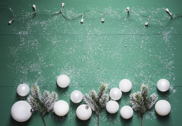 Seppele, kuusen oksat ja valkoiset joulupallot ovat vihreällä puisella pohjalla lumen peitossa. Joulun koostumus, tasainen, vaakasuora suunta, kopiotila - Valokuva, kuva