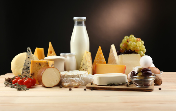 Tasty dairy products on wooden table, on dark background - 写真・画像