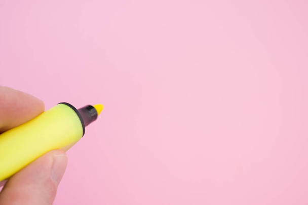A shot of fingers holding a yellow marker isolated on a bright background - Foto, afbeelding