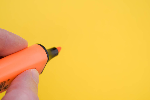 A shot of fingers holding an orange marker isolated on a bright background - Photo, image