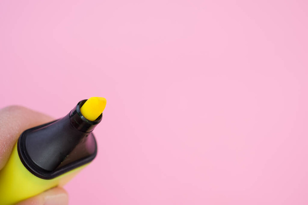 A shot of fingers holding a yellow marker isolated on a bright background - Foto, Bild