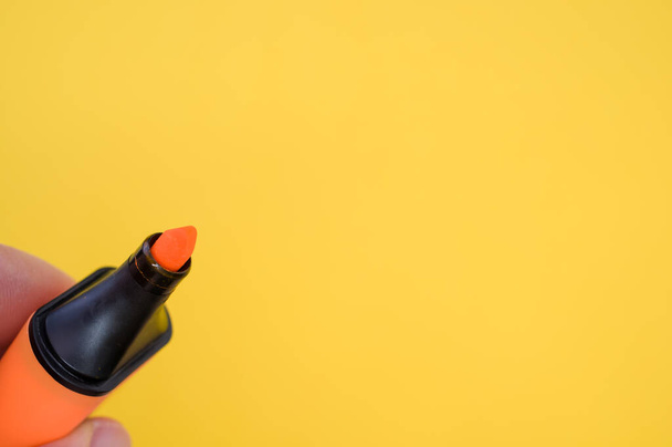 A shot of fingers holding an orange marker isolated on a bright background - Foto, afbeelding