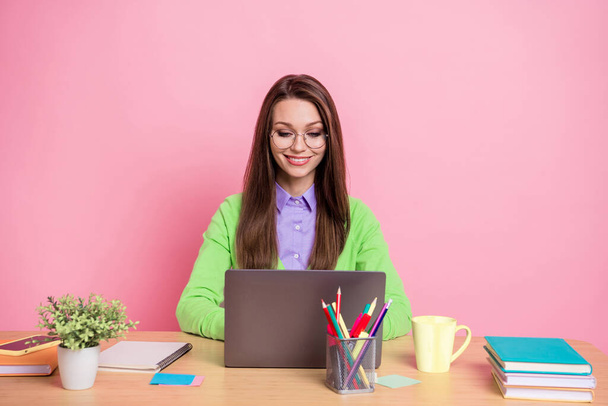 Portrait of focused girl sit table work laptop wear green shirt isolated over pastel color background - Valokuva, kuva