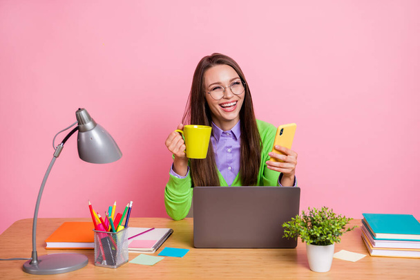 Positive high school girl sit table use digital smartphone laugh wear green shirt isolated pastel color background - Φωτογραφία, εικόνα