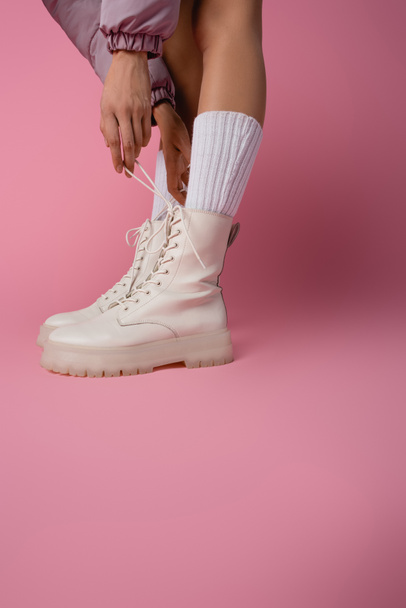 cropped view of female legs in boots and socks on pink background - Fotó, kép