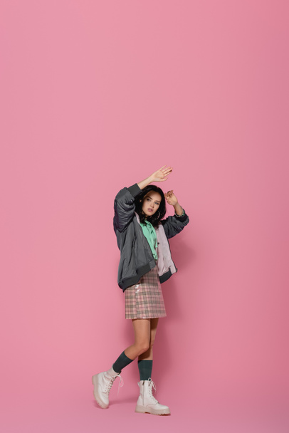 brunette young woman in casual winter outfit posing on pink background - Foto, afbeelding
