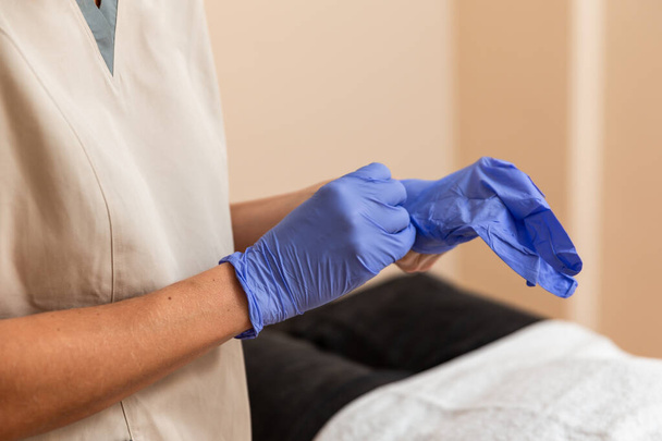 fisioterapista mette i guanti di lattice lilla accanto al paziente per la sessione di agopuntura - Foto, immagini