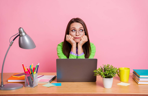 Sad upset girl sit desk work laptop look copyspace thoughtful wear green shirt isolated pastel color background - Foto, immagini