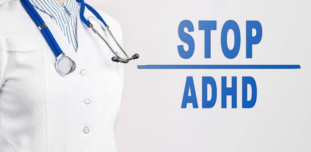 Tekst STOP ADHD na białym tle. W pobliżu znajduje się lekarz w białym płaszczu i stetoskopie. Koncepcja medyczna - Zdjęcie, obraz