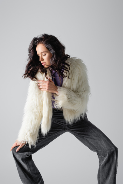 elegant brunette young woman in stylish faux fur jacket posing on white background - 写真・画像