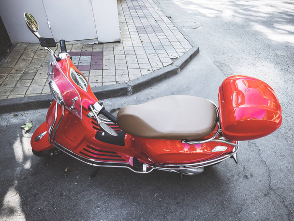 Red glossy motorcycle parked in a corner of the road near the walking sidewalk - Fotografie, Obrázek