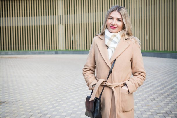 Beautiful blonde business woman in a long autumn coat in the city - Photo, image