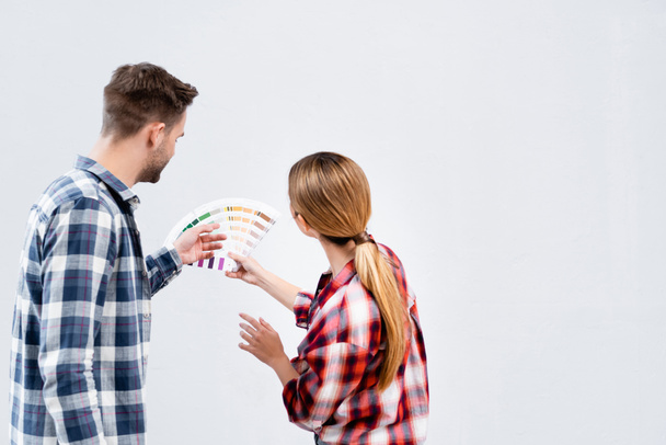 visão traseira do jovem casal com paleta selecionando a cor da parede isolada no branco - Foto, Imagem