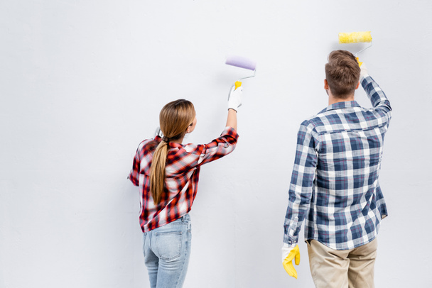 back view of young couple with rollers painting wall at home - Photo, Image