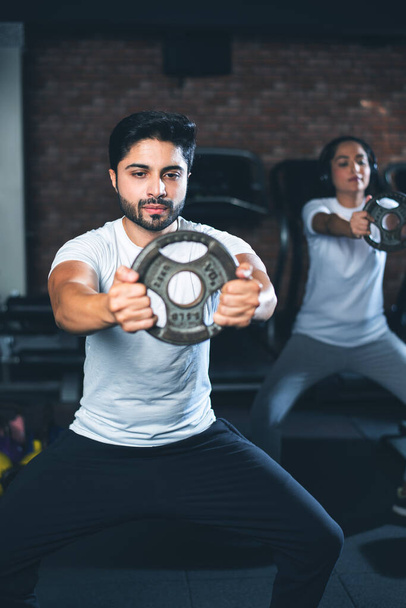 Indian asian Young couple is working out in the gym. Attractive woman and handsome fit man are training in modern gym - health and fitness concept - Photo, Image