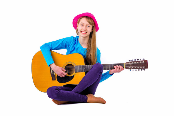 Une fille enfant joue de la guitare sur fond blanc dans le studio. - Photo, image