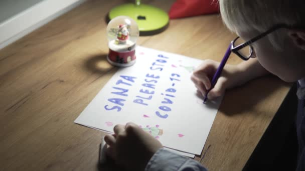 El chico rubio dibuja un cartel deseando Santa Claus con la inscripción q Santa - Metraje, vídeo