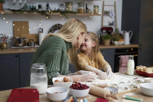 Mother and daughter lovingly in the kitchen while baking                                - Photo, Image