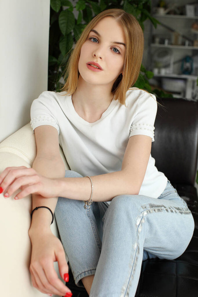 Blonde woman sitting on modern sofa - Фото, изображение