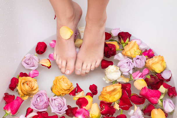 Nainen jalat kastettu kylpylä ja aromaterapia kulhoon ruusun terälehtiä ja päitä. Lähikuva valokuva kylpyhuoneessa. Kauneudenhoito - Valokuva, kuva