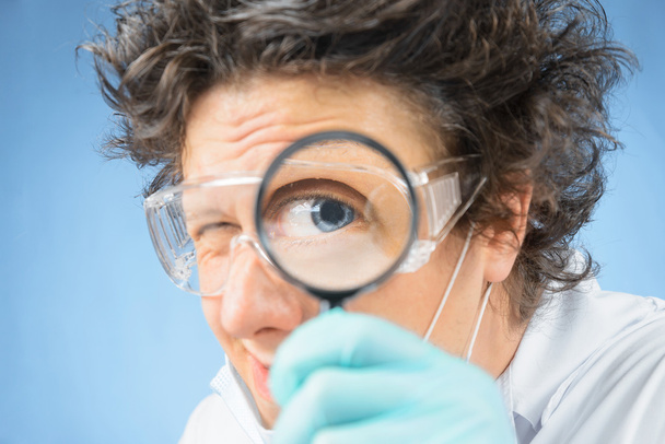 Scientist looks through a magnifying glass - Φωτογραφία, εικόνα