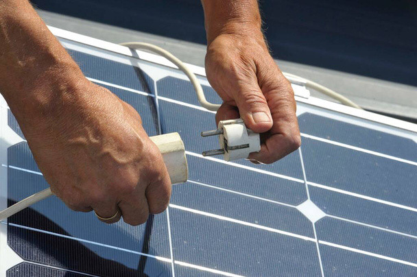 un enchufe eléctrico y panel solar, producción de energía sostenible y ecológica - Foto, Imagen