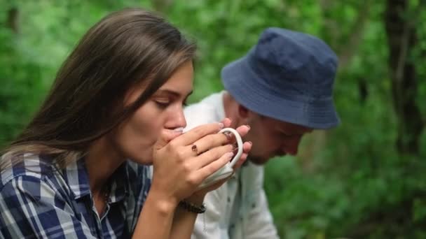 pysähtyä turisti ryhmä metsässä, nainen juo kuumaa teetä, mies lepää - Materiaali, video