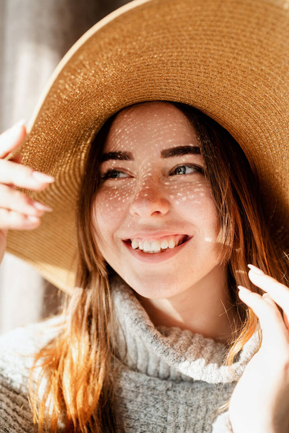 Světlo a stíny. Portrét krásné mladé ženy v slaměném klobouku se stínovým vzorem na obličeji a těle - Fotografie, Obrázek