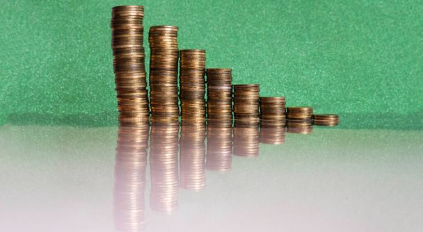 Монеты сложены в стопки и помещены на зеленом фоне.  - Фото, изображение