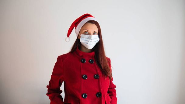 クリスマスの帽子とコロナビラスcovid-19マスクを持つ女性。テキストの負のスペースまたはコピースペース. - 写真・画像
