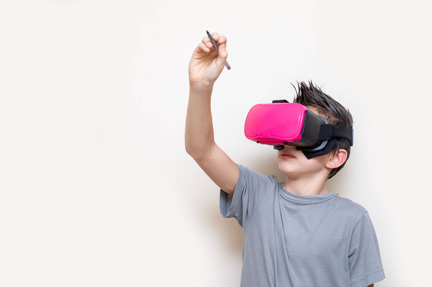 Jongen tiener in glazen van virtual reality Simulator ontvangt online onderwijs of speelt, schrijft over de virtuele ruimte. Modern onderwijs met behulp van digitale technologieën. Foto close-up - Foto, afbeelding