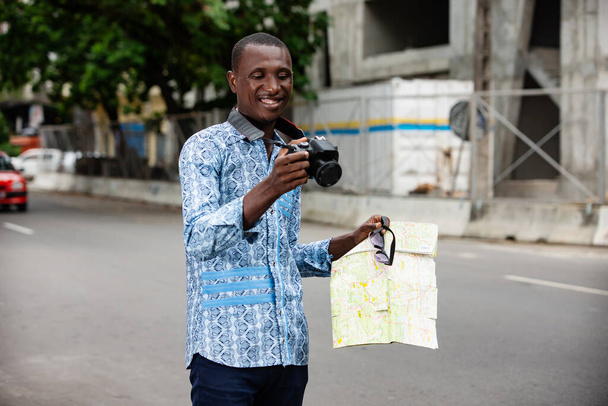 Счастливый молодой человек фотограф смотрит снимки сделал туристические места с его камерой и смеется - Фото, изображение