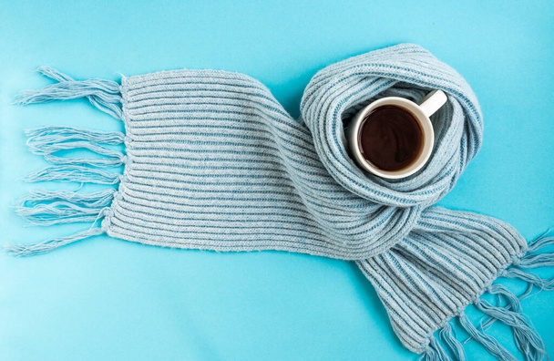Taza blanca de té con bufanda azul sobre fondo azul. Concepto de enfermedad y salud. - Foto, imagen