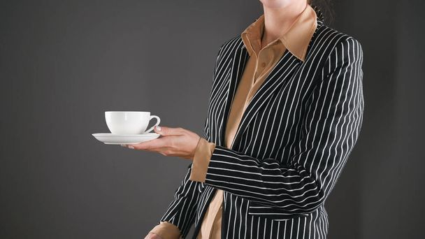 Woman in a suit with a white cup, on a dark background. High quality photo - Photo, image