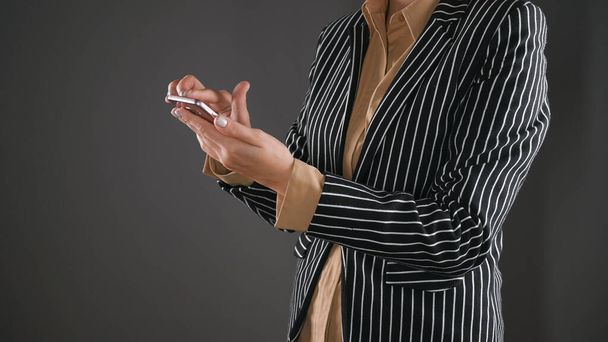 A Woman in a suit reads the news on the phone. High quality photo - Foto, afbeelding