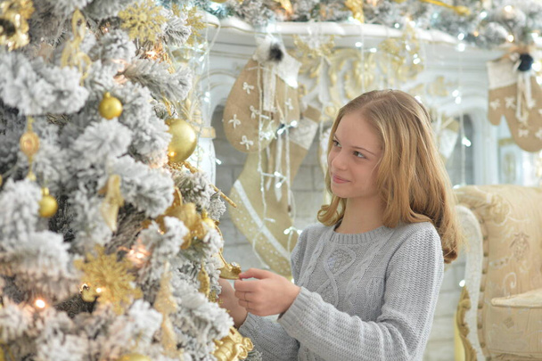 beautiful girl decorating Christmas tree at home - Fotó, kép