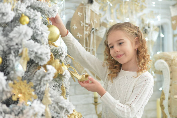 happy girl decorating Christmas tree at home - Fotó, kép