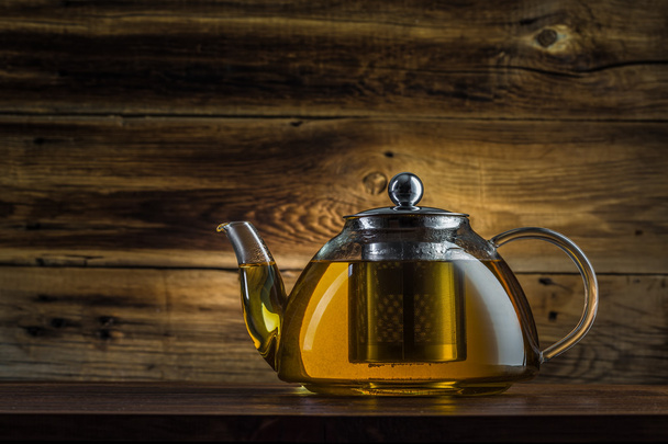 glass teapot with green tea on a wooden background - Foto, imagen