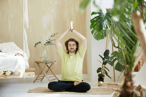handsome male practicing yoga at home, adult doing yoga asana sitting in lotus asana, mindfullness concept - Photo, Image