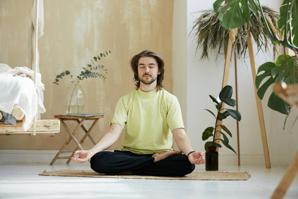 schöner Mann, der in Meditation, Meditation und Konzentrationskonzept sitzt, friedlicher Typ, der meditiert und die Arme in Yoga-Mudra hält - Foto, Bild