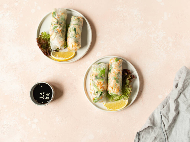 Involtini primavera vietnamiti con insalata, salsa, granchio e tagliatelle su piatti e salsiccia in ciotola su sfondo rosa. vista dall'alto. copia spazio - Foto, immagini